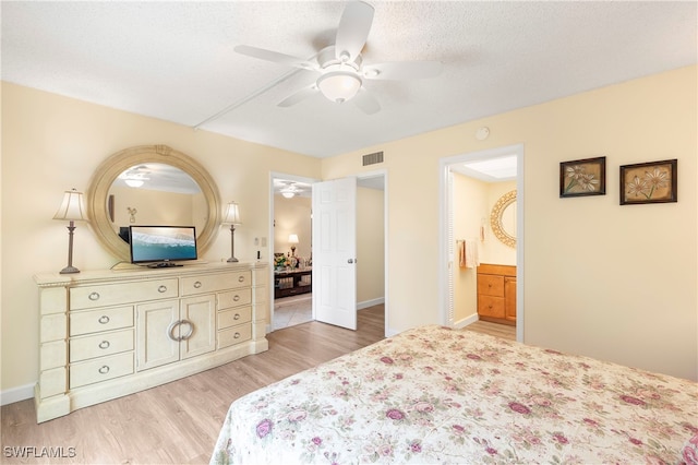 bedroom with a textured ceiling, connected bathroom, light hardwood / wood-style floors, and ceiling fan