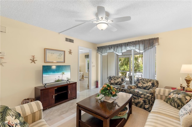 living room with ceiling fan and a textured ceiling