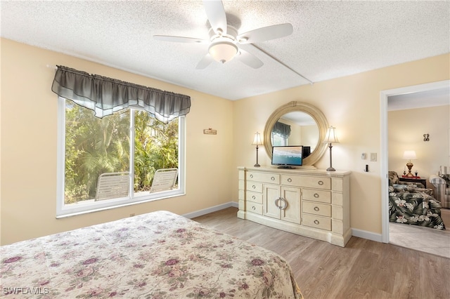 bedroom featuring ceiling fan, light wood-type flooring, and a textured ceiling