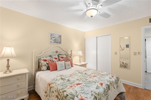 bedroom with a closet, ceiling fan, dark hardwood / wood-style flooring, and a textured ceiling