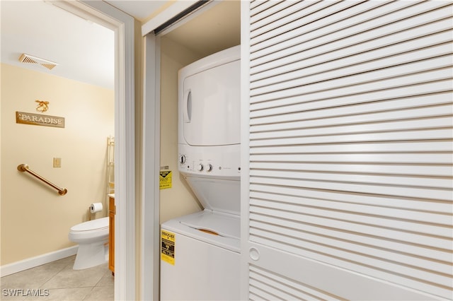 clothes washing area featuring light tile patterned floors and stacked washer and clothes dryer