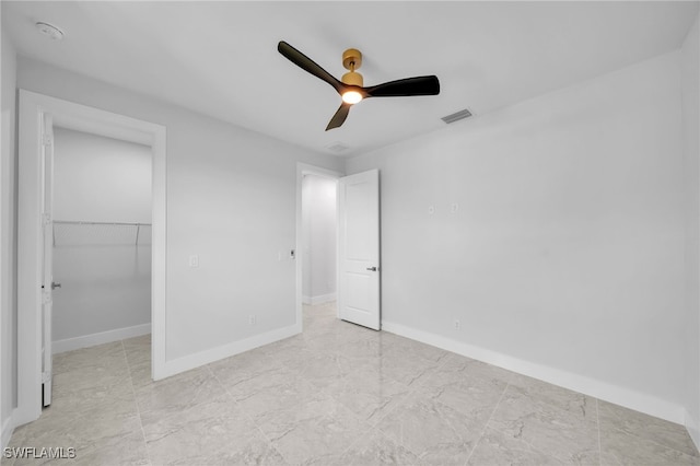 unfurnished bedroom featuring ceiling fan, a walk in closet, and a closet