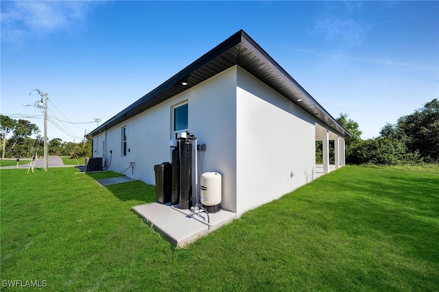 rear view of property featuring a lawn and central air condition unit