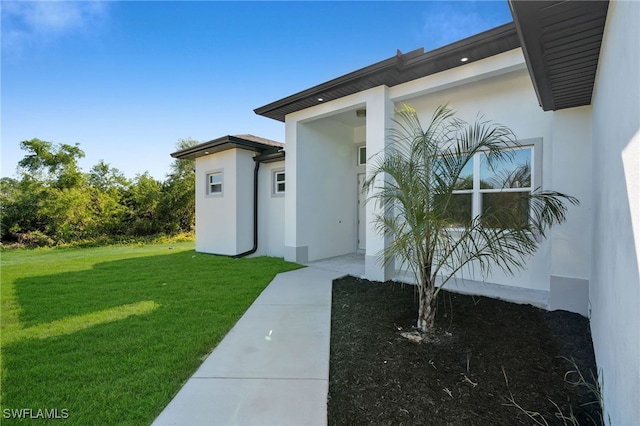 view of exterior entry featuring a lawn