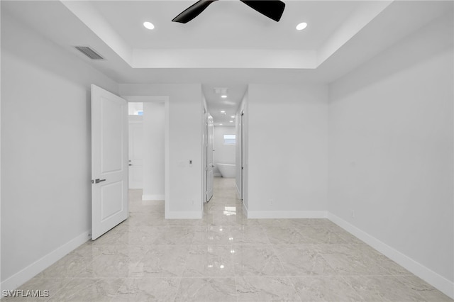 unfurnished bedroom featuring a raised ceiling and ceiling fan