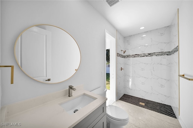 bathroom with tiled shower, vanity, and toilet