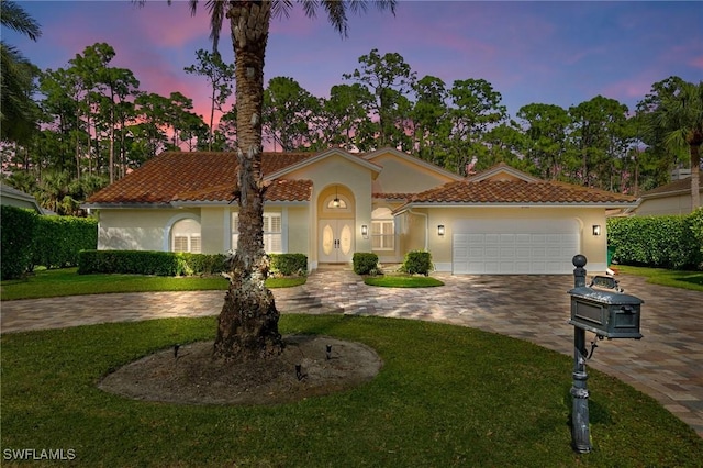 mediterranean / spanish-style house featuring a yard and a garage