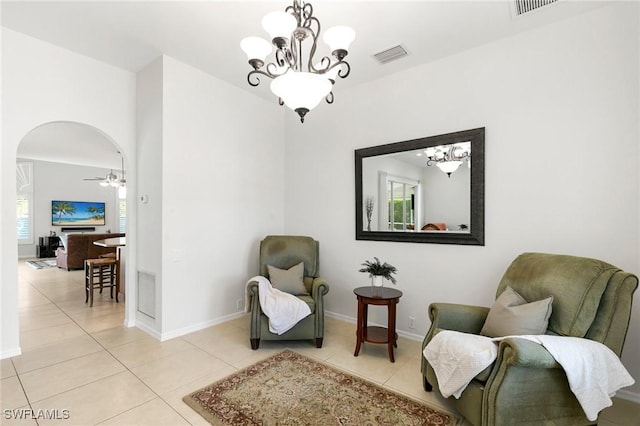 sitting room with light tile patterned flooring and ceiling fan with notable chandelier