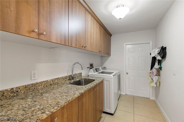 laundry area featuring cabinets, light tile patterned floors, sink, and washing machine and clothes dryer