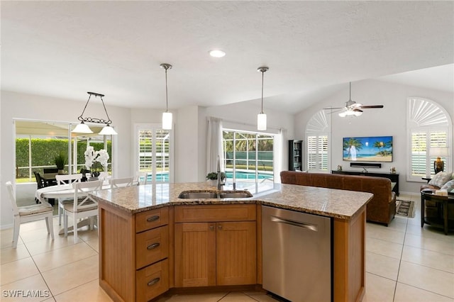 kitchen with lofted ceiling, light stone counters, stainless steel dishwasher, hanging light fixtures, and an island with sink