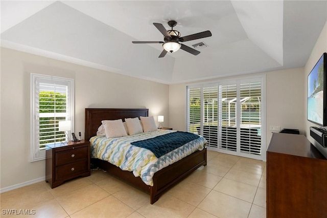 bedroom with a raised ceiling, light tile patterned floors, ceiling fan, and access to outside