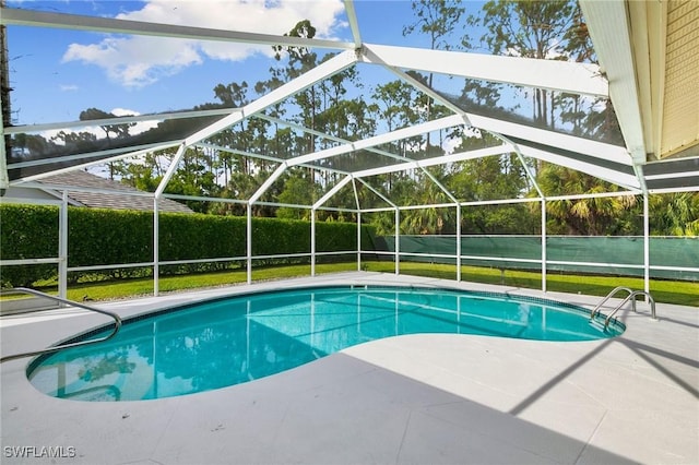 view of swimming pool with a patio, glass enclosure, and a lawn