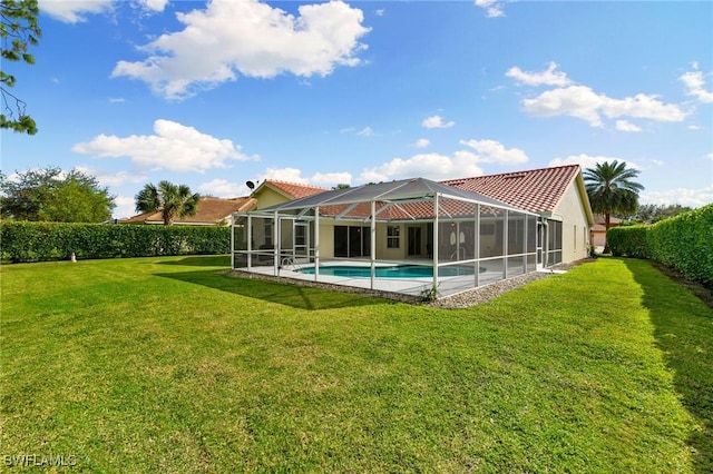 rear view of property featuring glass enclosure, a lawn, and a fenced in pool