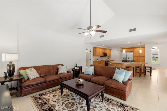 tiled living room with ceiling fan, sink, and high vaulted ceiling