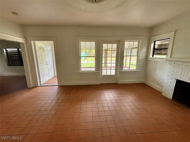 unfurnished living room with tile patterned flooring, a fireplace, and a wealth of natural light