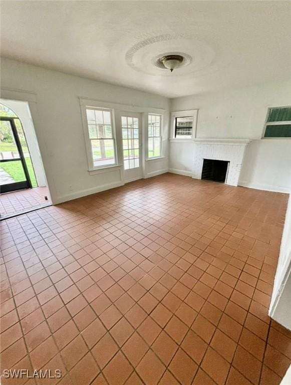 unfurnished living room featuring a fireplace and light tile patterned flooring