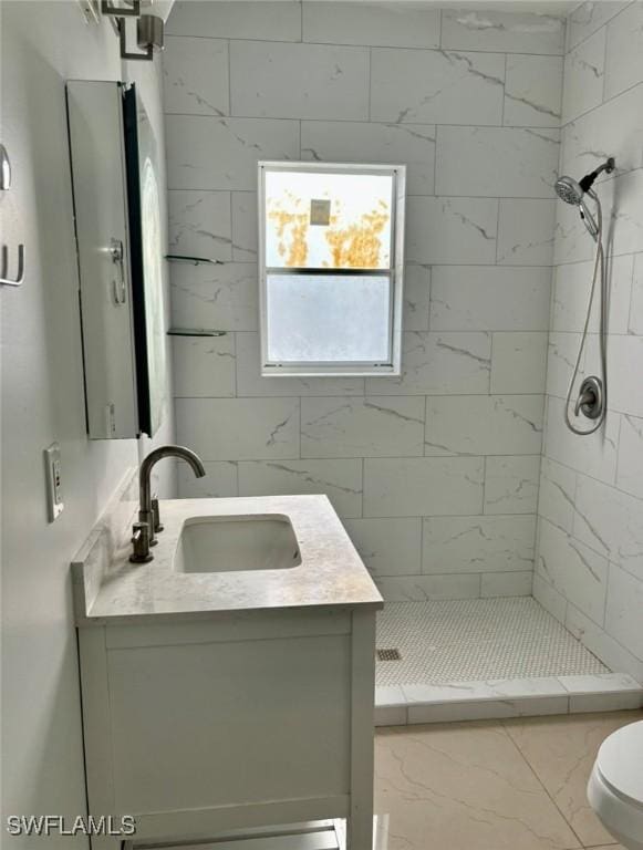 bathroom with tiled shower, vanity, and toilet