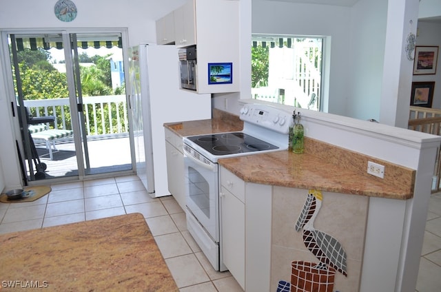 kitchen featuring white cabinets, light tile patterned flooring, plenty of natural light, and electric stove