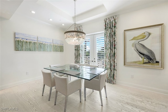 dining space featuring french doors, light hardwood / wood-style floors, a raised ceiling, and a notable chandelier