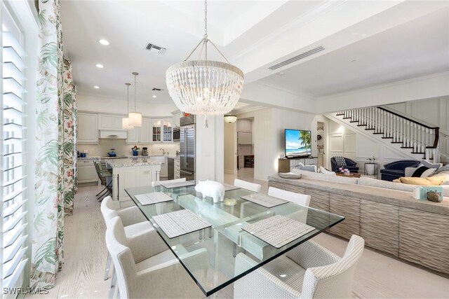 dining space with light hardwood / wood-style flooring, crown molding, and a chandelier