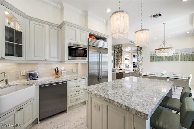 kitchen with tasteful backsplash, stainless steel appliances, an inviting chandelier, white cabinetry, and hanging light fixtures