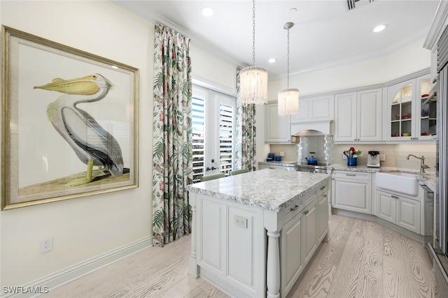 kitchen featuring pendant lighting, backsplash, light hardwood / wood-style floors, ornamental molding, and a kitchen island