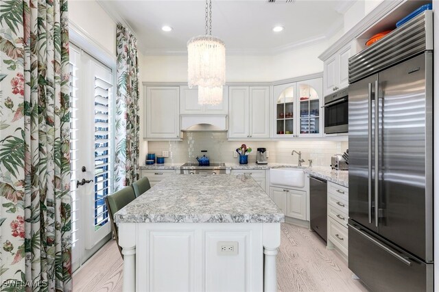 kitchen with white cabinetry, a center island, sink, stainless steel appliances, and crown molding