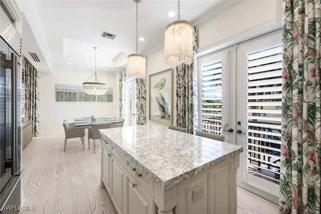 kitchen with light hardwood / wood-style floors, a kitchen island, and a notable chandelier