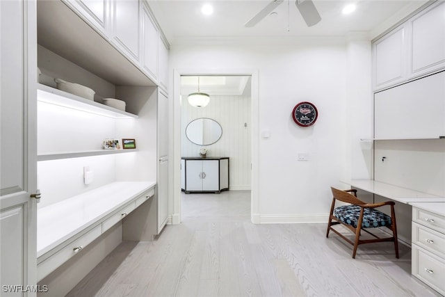 office area with built in desk, light hardwood / wood-style floors, ceiling fan, and ornamental molding