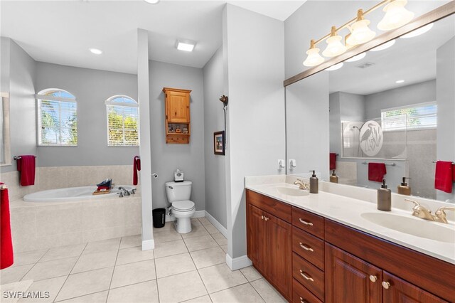 bathroom featuring tile patterned flooring, vanity, tiled tub, and toilet