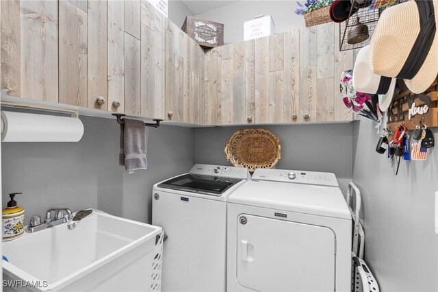 clothes washing area featuring cabinets, sink, and washer and dryer