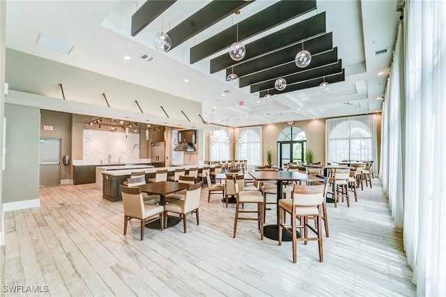 dining space featuring beam ceiling, light wood-type flooring, and coffered ceiling