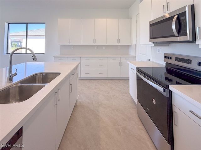 kitchen with white cabinets, light tile patterned floors, sink, and appliances with stainless steel finishes