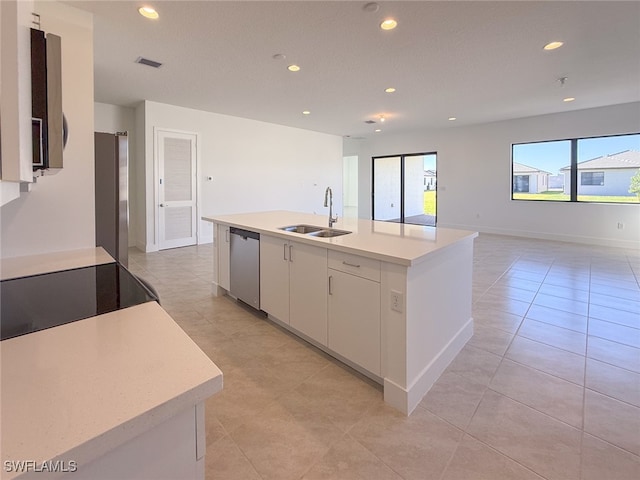 kitchen featuring appliances with stainless steel finishes, sink, light tile patterned floors, white cabinets, and an island with sink