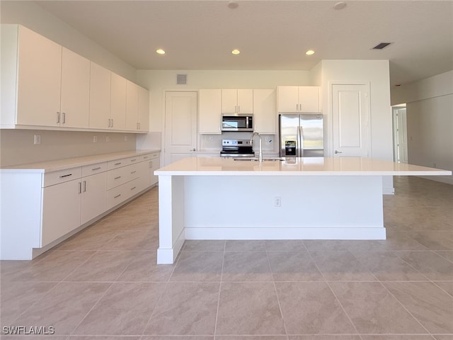 kitchen featuring sink, light tile patterned floors, an island with sink, white cabinetry, and stainless steel appliances