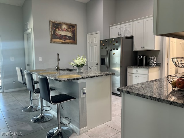 kitchen with stainless steel fridge, sink, white cabinets, and light tile patterned flooring