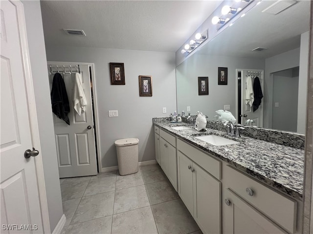 bathroom with tile patterned flooring, vanity, and a textured ceiling