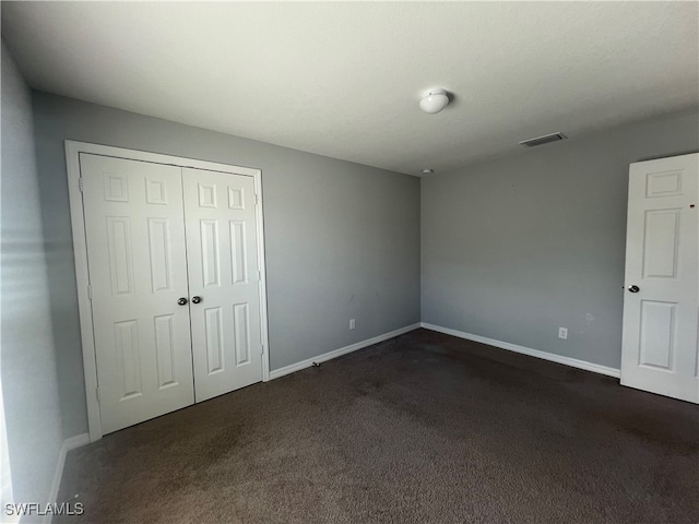 unfurnished bedroom featuring a closet and dark carpet