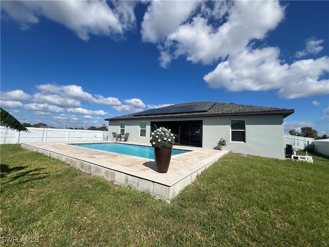 back of house featuring solar panels, a yard, a fenced in pool, and a patio