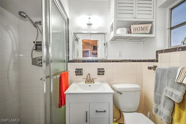 bathroom featuring vanity, toilet, tile walls, and a shower with shower door