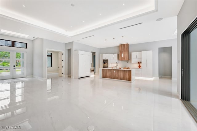 living room featuring french doors, a raised ceiling, and sink