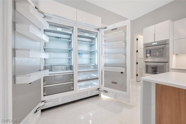 kitchen featuring refrigerator, white cabinetry, and double oven