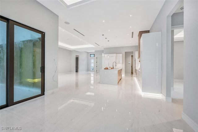 hall with sink and a tray ceiling