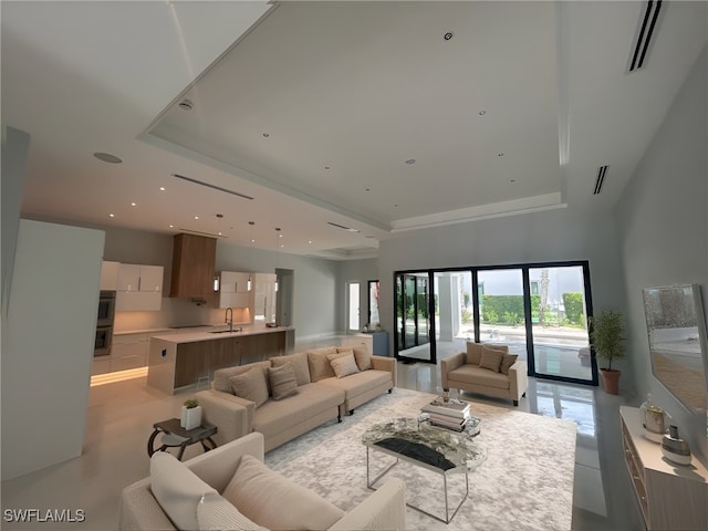 living room with a tray ceiling and sink