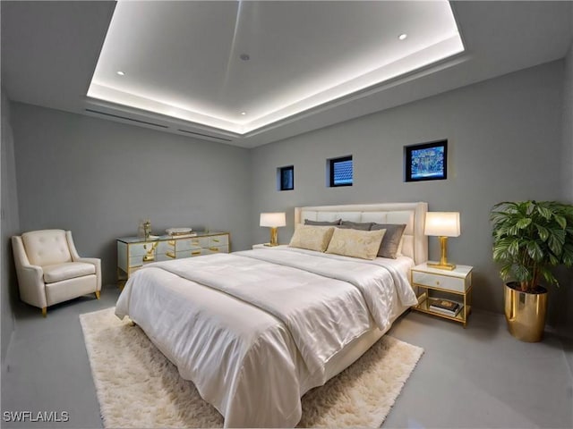 bedroom with concrete floors and a raised ceiling