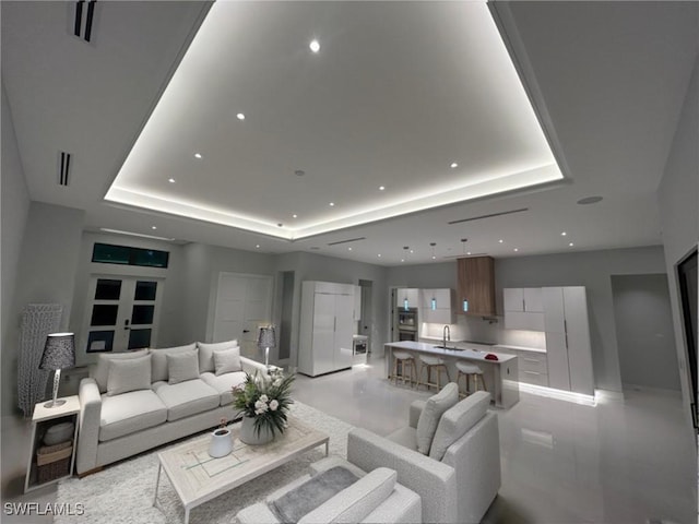 living room featuring a raised ceiling and sink