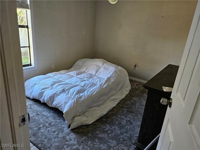 bedroom with dark colored carpet and multiple windows