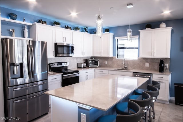 kitchen with a kitchen island, white cabinetry, sink, and appliances with stainless steel finishes