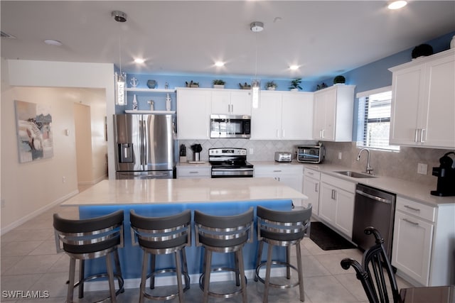 kitchen with white cabinetry, sink, a center island, pendant lighting, and appliances with stainless steel finishes