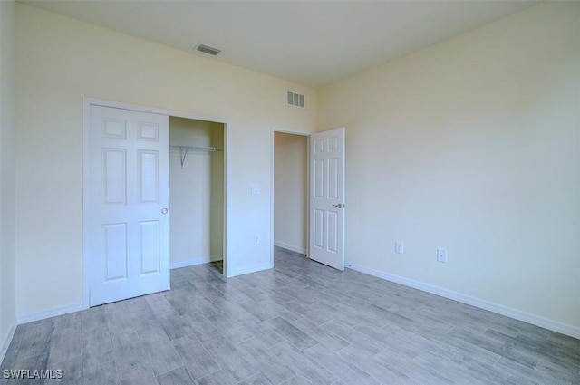 unfurnished bedroom with light wood-type flooring and a closet